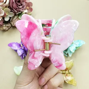Close-up of pink gradient butterfly hair claw clip with golden metal spring and smooth finish