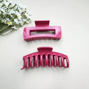 Detailed view of two rose red soft silicone hair claw clips on a minimalist beige desk
