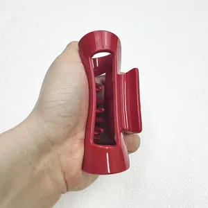 Detail of a large dark red matte silicone claw clip held by hand to show size and scale