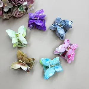 Flat lay of six double-layered marble butterfly hair claws in various sweet pastel colors