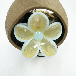 Detailed view of the yellow flower hair claw clip with blue edges on a ceramic base
