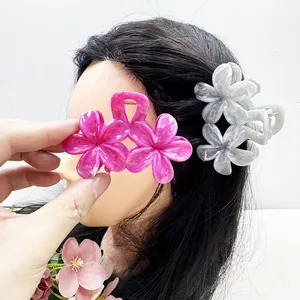 Détail de pinces à cheveux doubles fleurs de frangipanier en résine fuchsia et marbrée