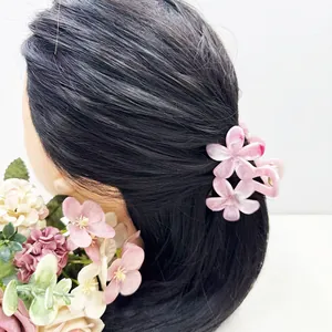 Vue détaillée d'une pince à cheveux fleurs roses en dégradé sur une chevelure brune