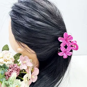 Pince à cheveux fleur de frangipanier rose foncé portée pour un style de vacances chic