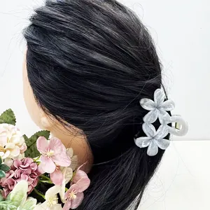 Détail d'une pince à cheveux double fleur en acétate marbré gris sur cheveux foncés