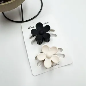 Detailansicht kleiner matter Plumeria-Blüten-Haarklammern in Schwarz und Weiß auf Karte