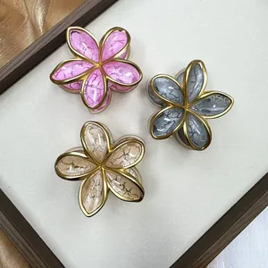 Detail of three plumeria hair claws in pink, grey and champagne with crackle finish