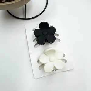 Detail von matten schwarz-weißen Frangipani-Haarklammern auf Schmuck-Präsentationskarte