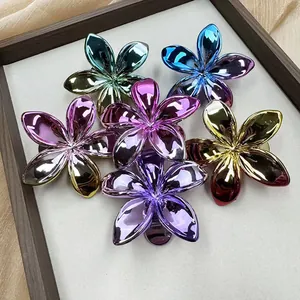 Plated Frangipani flower metal hair clips in various gradient colors on silk background
