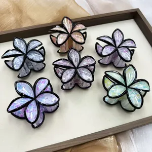 Set di sei mollette per capelli floreali colorate con glitter e bordi neri su vassoio