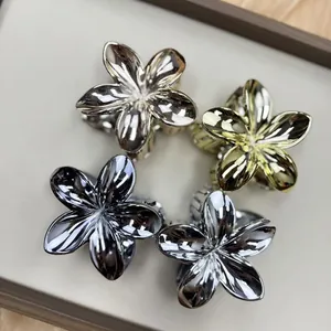 Detailed overhead view of metallic frangipani flower hair claws in four elegant finishes