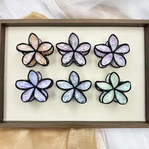 Set di sei mollette per capelli a forma di fiore colorato con glitter su un vassoio