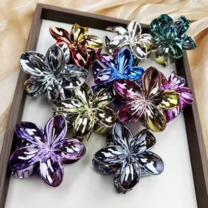 Close-up of assorted metallic frangipani flower hair claws on a satin-lined wooden tray