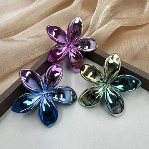 Detailed macro view of three metallic plated plumeria flower hair clips in vibrant gradients
