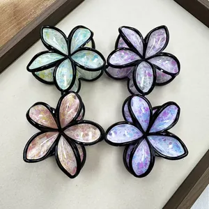 Detailed top view of four floral claw clips with colorful ink-splatter art textures