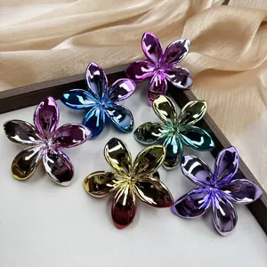 Close-up of metallic plumeria flower hair clips in six colors on elegant silk fabric