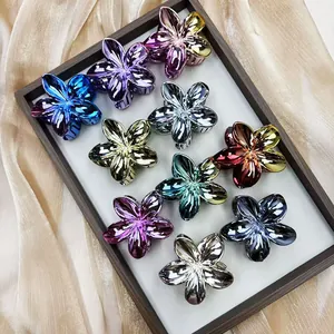 Plated metal frangipani hair clips in various colors displayed on a silk lined tray