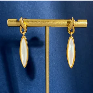 Dettaglio di orecchini vintage in oro con intarsio in madreperla su sfondo in velluto blu