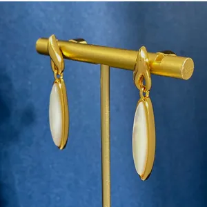 Dettaglio di orecchini vintage dorati con inserti ovali in madreperla bianca lucida
