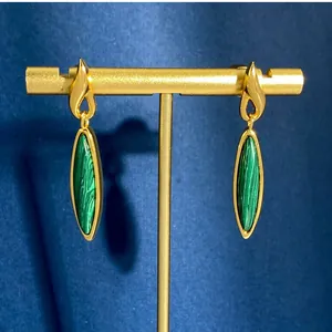 Dettaglio di orecchini dorati con malachite a marquise su un espositore di velluto