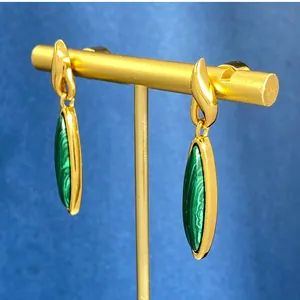 Dettaglio di orecchini vintage con intarsio in malachite verde su supporto dorato