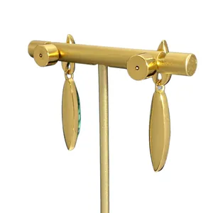 Orecchini a pendente dorati vintage con inserto verde esposti su supporto in metallo a T