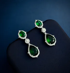Macro-opname van smaragdgroene waterdruppel oorbellen met diamanten en zilveren plating
