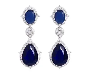 Detailweergave van zilveren oorbellen met blauwe druppelstenen en pavé gezette kristallen