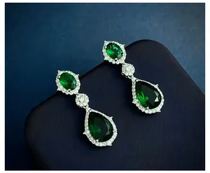 Detailopname van de smaragdgroene druppeloorbellen in een blauw sieradendoosje