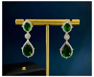 Detailopname van smaragdgroene druppeloorbellen met zilveren zirkonia-accenten