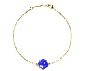 Detail van gouden kettingarmband met een grote blauwe kristal en stevige karabijnsluiting