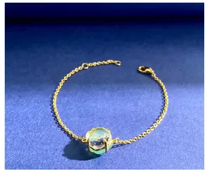 Detail van een lichtgroene facetgeslepen kristalsteen op een gouden damesarmband