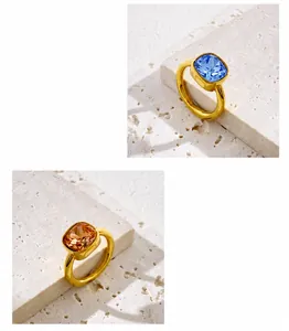 Detail of square-cut crystal rings in blue and champagne on a stone pedestal