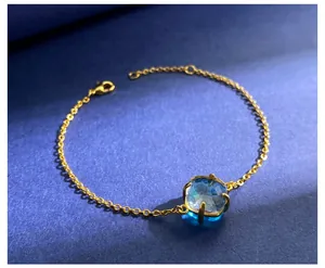 Detail van de gouden armband met een vierkante lichtblauwe edelsteen en een karabijnsluiting