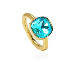 Macro detail of cushion cut blue crystal gemstone set in a minimalist gold band ring