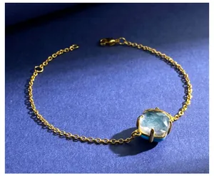 Macro detail van vergulde kettingarmband met vierkante blauwe kristal en karabijnslot