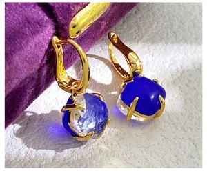 Detaillierte Makroansicht der goldenen Brisur-Ohrringe mit facettierten blauen Kristallen