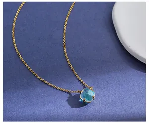 Makroaufnahme einer hellblauen Edelsteinkette mit Goldkette auf dunkler Textur