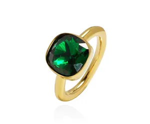 Close-up of golden ring featuring a large square-cut green emerald gemstone