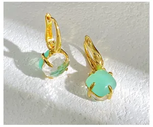 Detailansicht goldener Ohrringe mit smaragdgrünen und weißen quadratischen Kristallsteinen