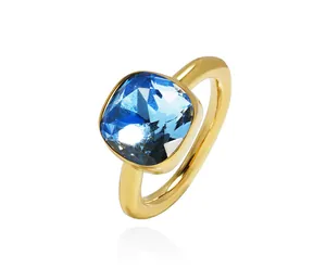 Macro view of a gold-plated ring with a faceted square blue gemstone on white background