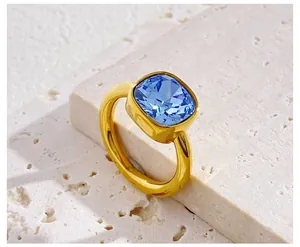 Detail of a square-cut blue gemstone set on a thick gold band over a white stone base