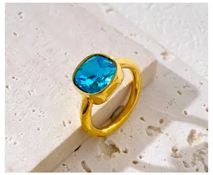 Macro view of a gold-plated ring with a square-cut bright blue crystal and bezel setting