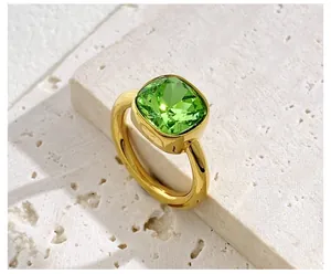 Macro shot of square emerald green crystal cocktail ring with polished gold band