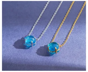 Details von blauen Kristallanhängern in Gold- und Silberfassungen an feinen Ketten