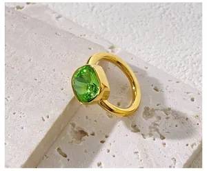 Detail of a square cushion-cut green crystal ring with thick polished gold-plated band