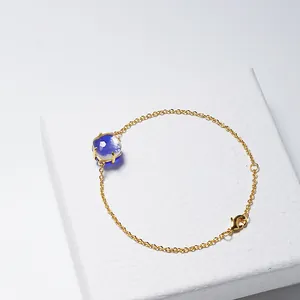 Elegante gouden kettingarmband met vierkant geslepen blauwe kristal op een juwelendoos