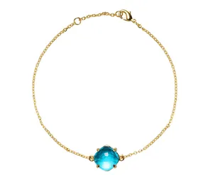 Detailweergave van de gouden armband met een gefacetteerd blauw kristal in een vierpootzetting