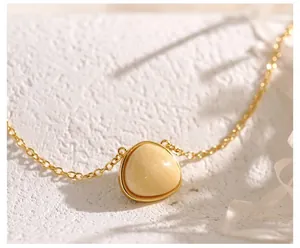 Macro detail of triangle amber gemstone pendant on a fine gold-plated cross chain