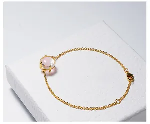 Detailopname van een gouden armband met een gefacetteerd roze kristal in een klassieke vierklauwzetting